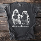 Dark gray t-shirt with a black and white graphic of two birds and "attempted murder" text.