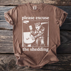 Brown t-shirt with graphic of a werewolf by a sink, text says "please excuse the shedding".