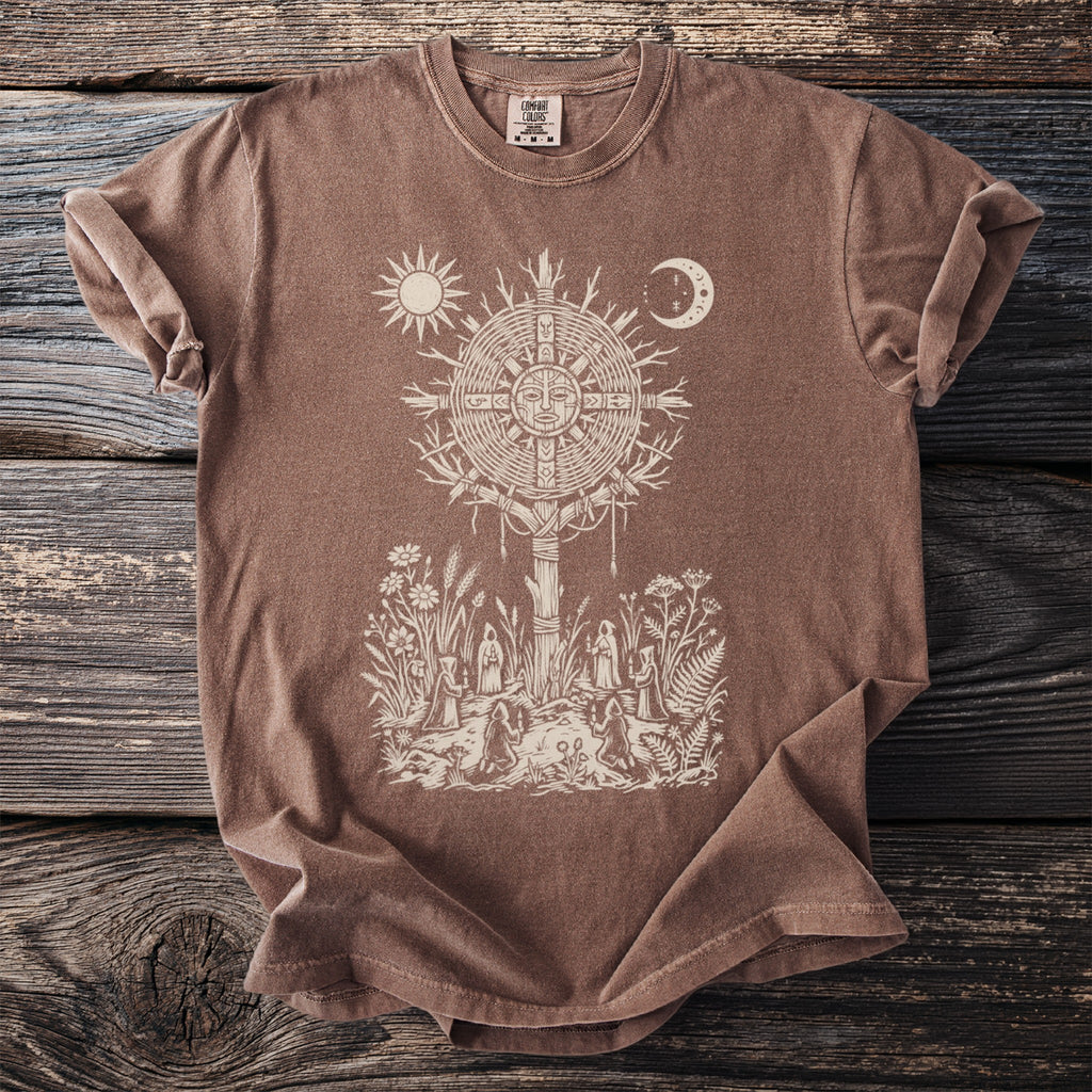 Brown t-shirt with a cream graphic of a sun and moon over a ritual scene.