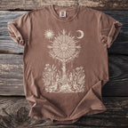 Brown t-shirt with a cream graphic of a sun and moon over a ritual scene.