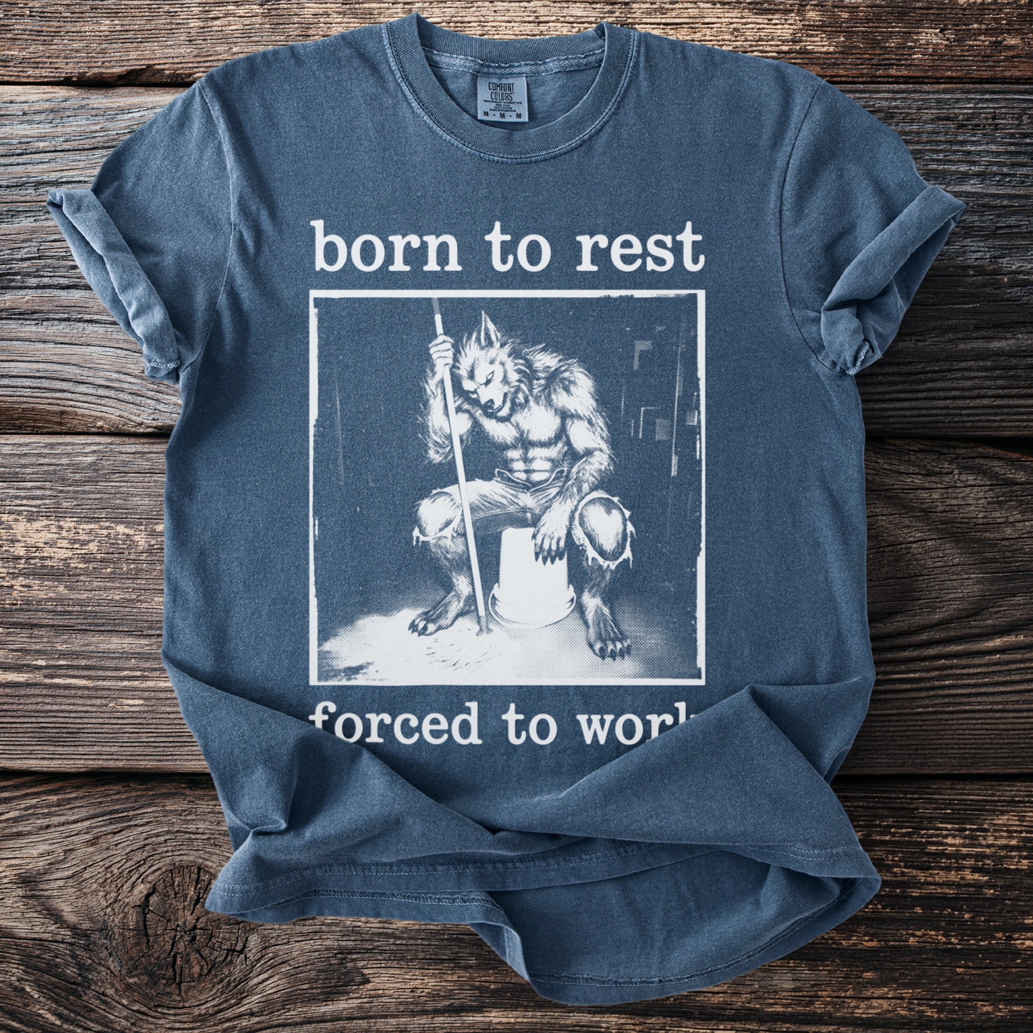 Blue t-shirt with graphic of werewolf sitting on bucket saying "born to rest forced to work".
