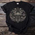 Black t-shirt with a cream-colored circular design of a dragonfly, sun, moon, and flowers.