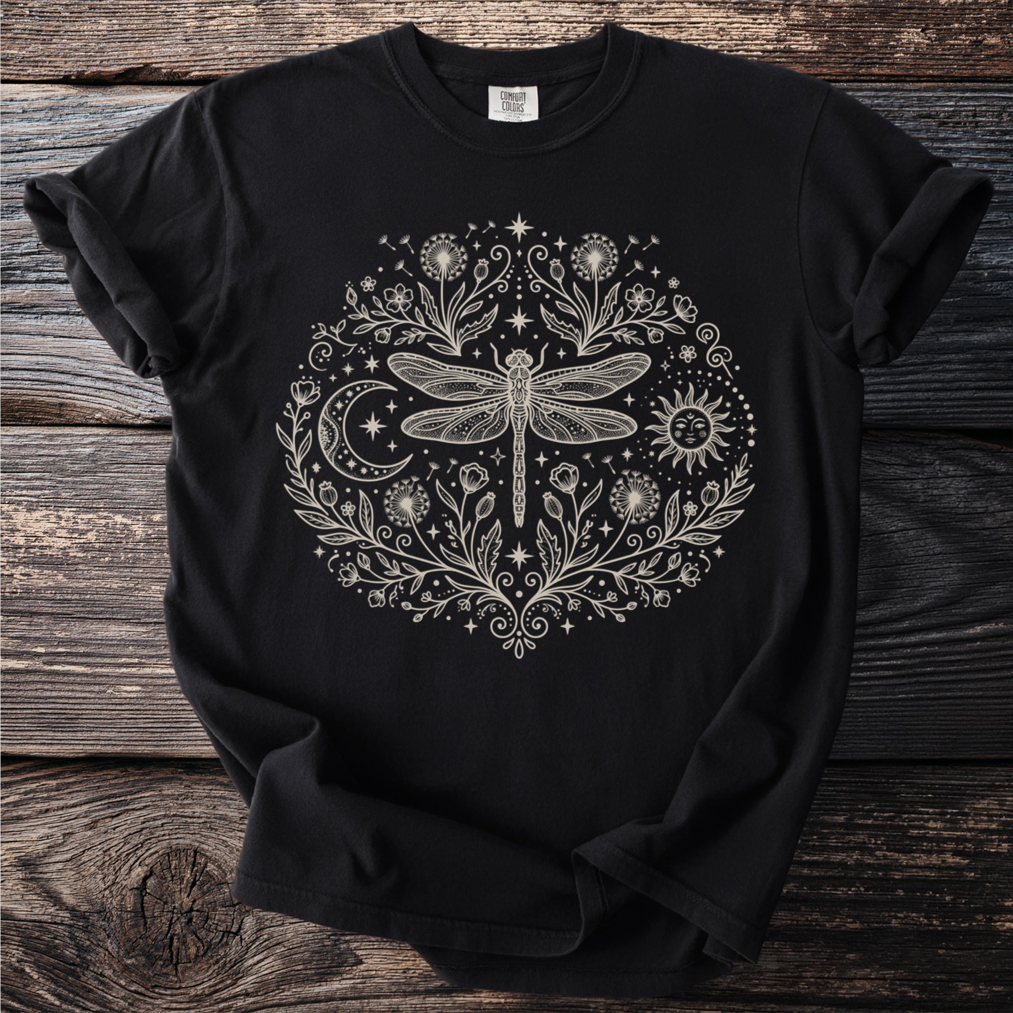 Black t-shirt with a cream-colored circular design of a dragonfly, sun, moon, and flowers.