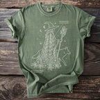 Green t-shirt with white line art of a witch, a fox, and botanical elements.