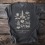 Dark t-shirt with "The Wildflower Meadow" botanical illustration featuring labeled wildflowers and scientific names.