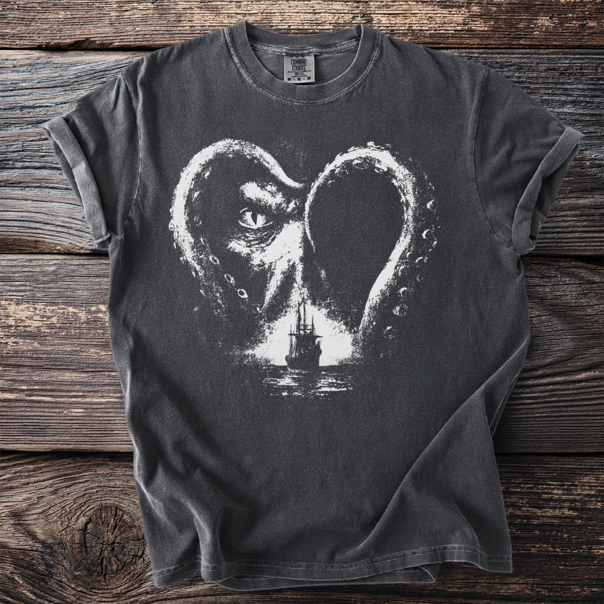 Dark t-shirt with a white Kraken heart graphic surrounding a sailing ship.