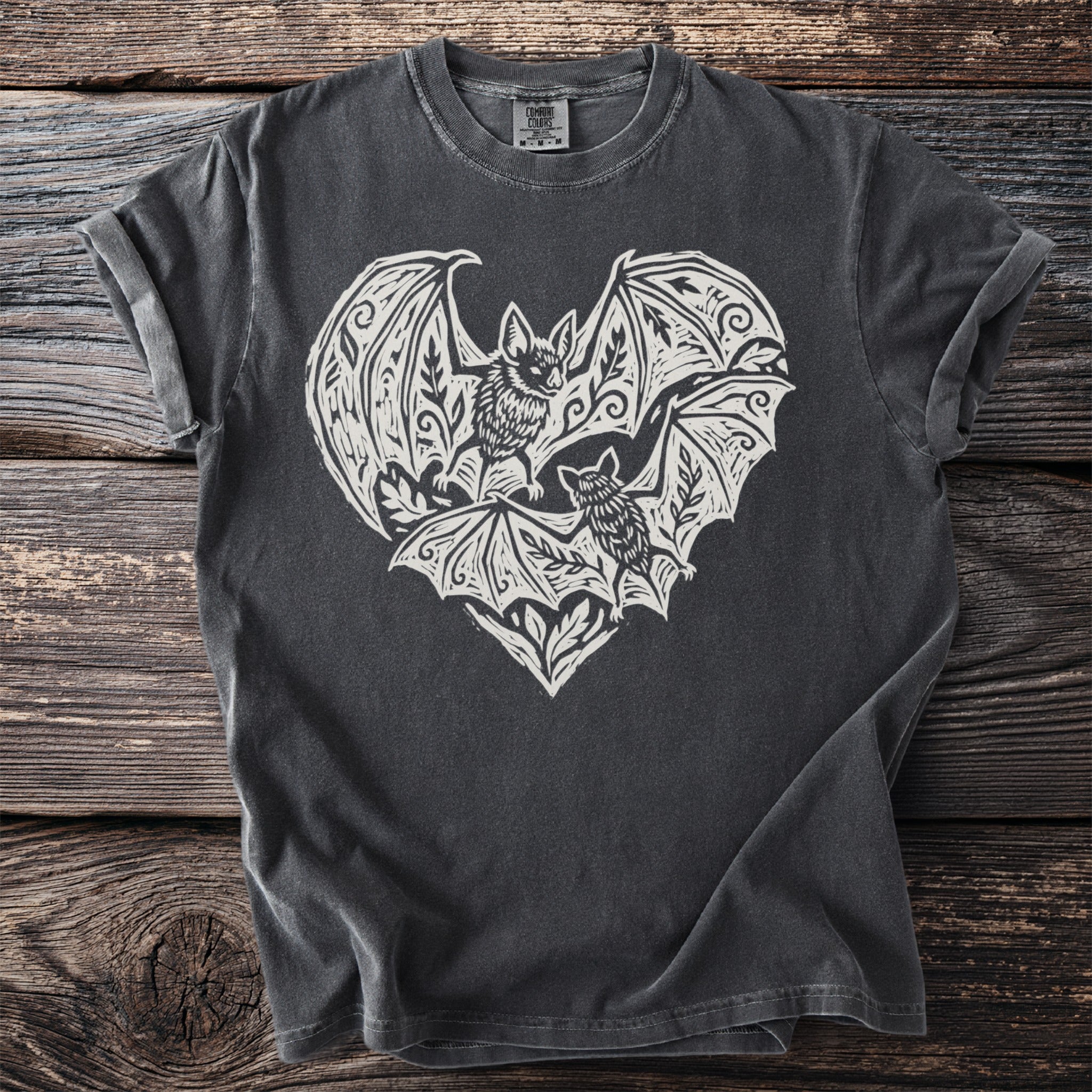 Dark gray t-shirt with a white linocut-style print of two bats within a heart shape.