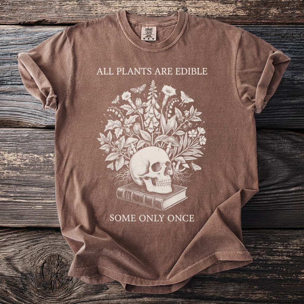 Brown t-shirt with a skull, book, and botanical design. "All plants are edible" and "Some only once" text.