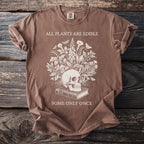 Brown t-shirt with a skull, book, and botanical design. "All plants are edible" and "Some only once" text.