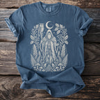 Blue t-shirt with cream print of a wizard with an owl, moon, and forest elements.