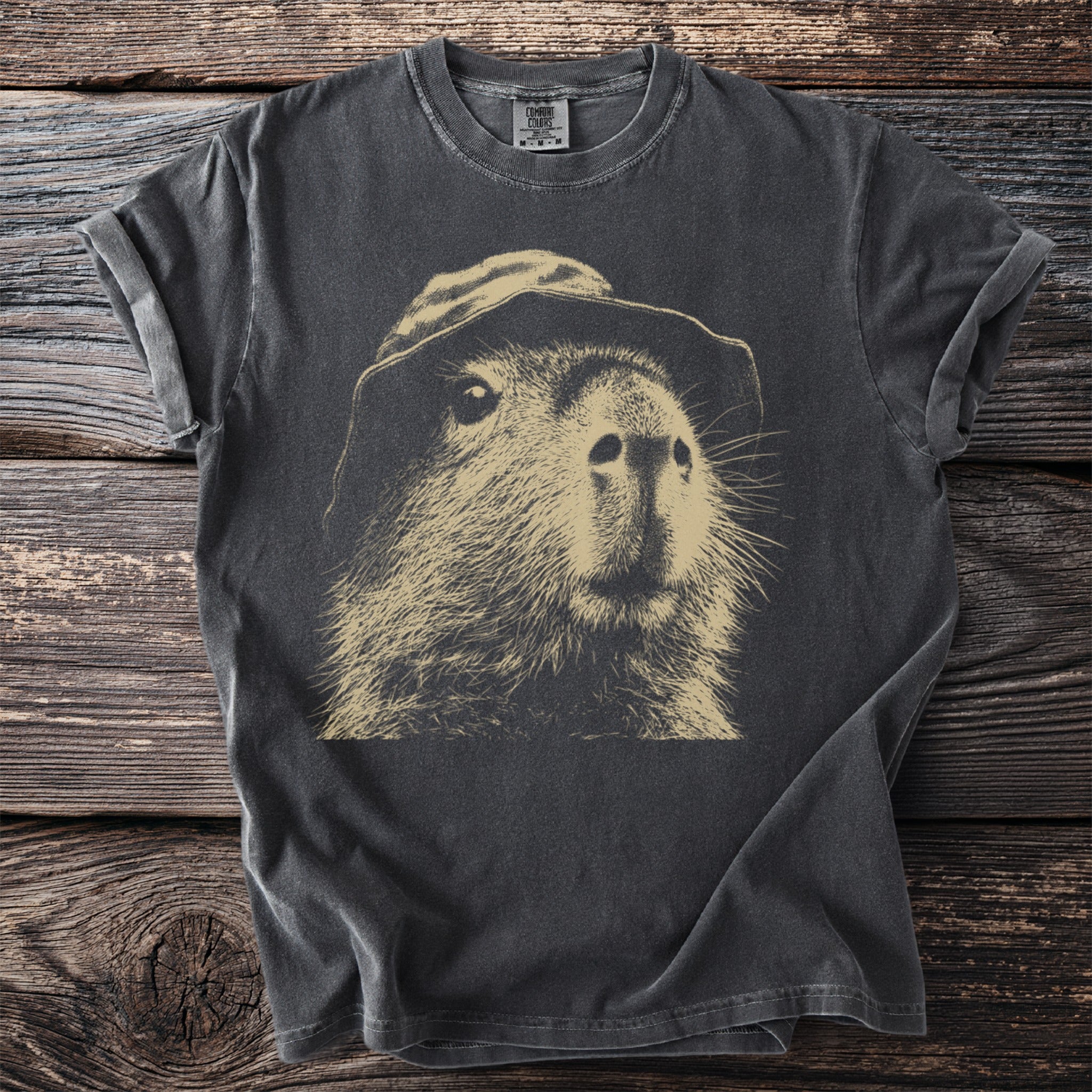Dark t-shirt with a vintage sketch of a capybara wearing a hat.