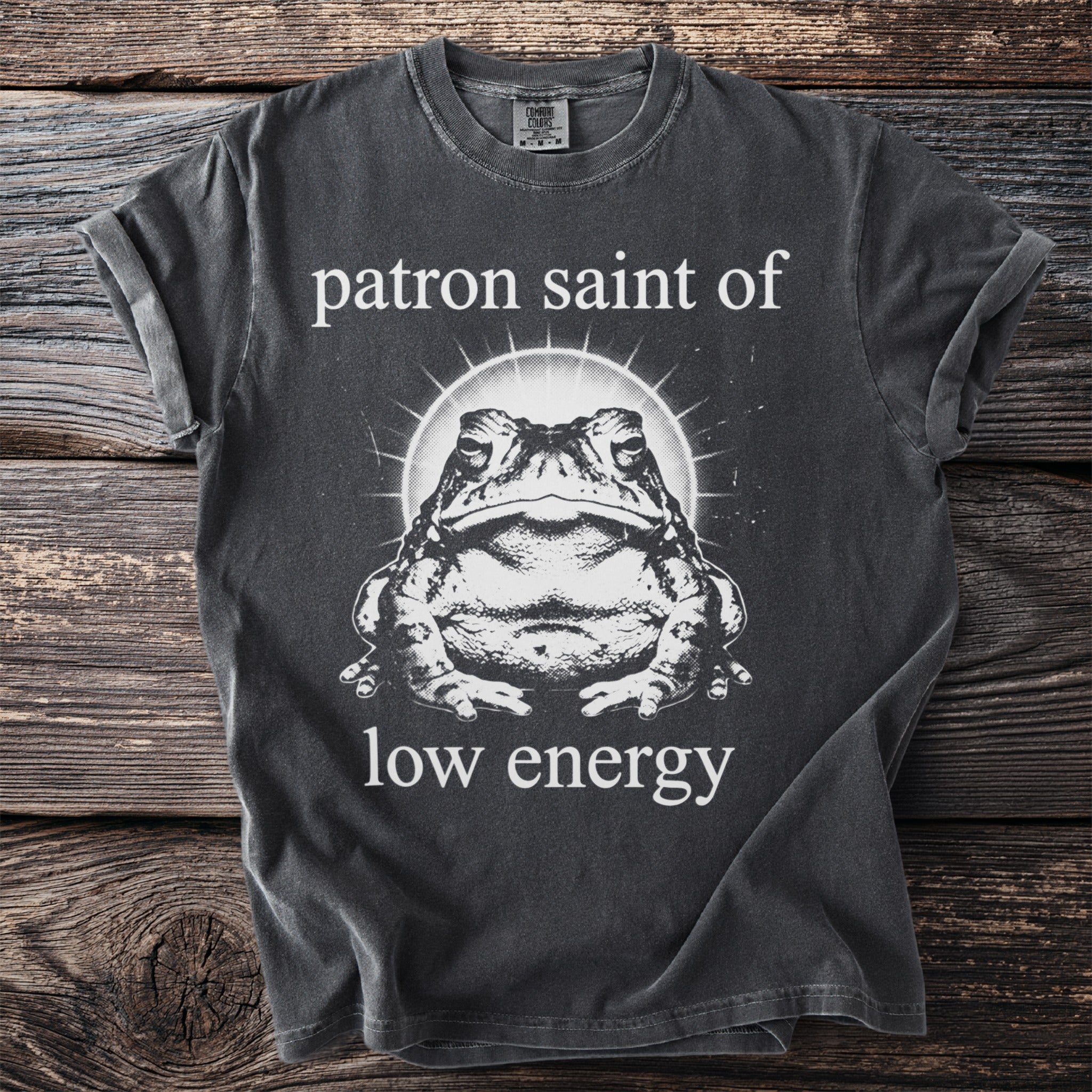 Dark grey t-shirt with white text and graphic of a toad: "patron saint of low energy"