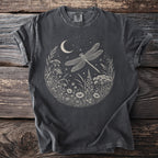 Dark t-shirt with a circular print of a dragonfly, moon, and wildflowers under a starry sky.