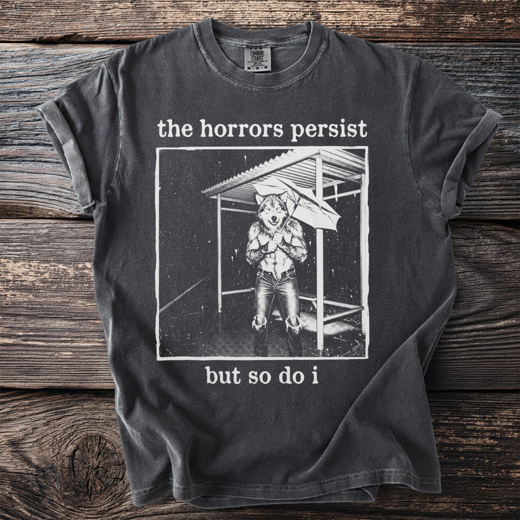 Charcoal t-shirt with graphic of wolf in rain and text "the horrors persist but so do i".