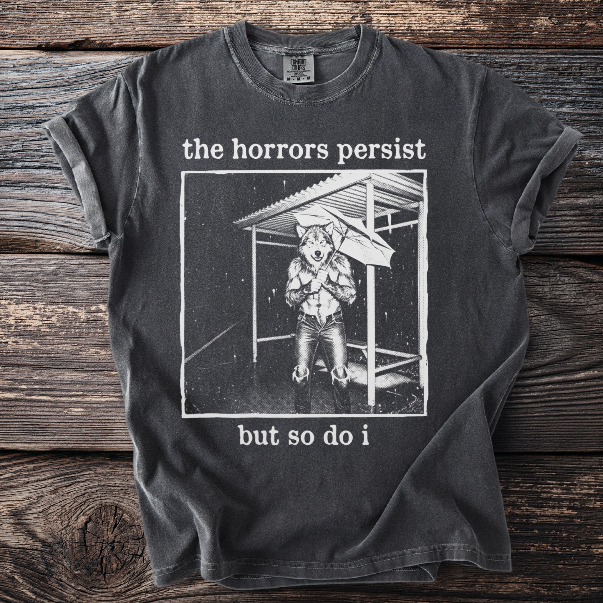 Charcoal t-shirt with graphic of wolf in rain and text "the horrors persist but so do i".