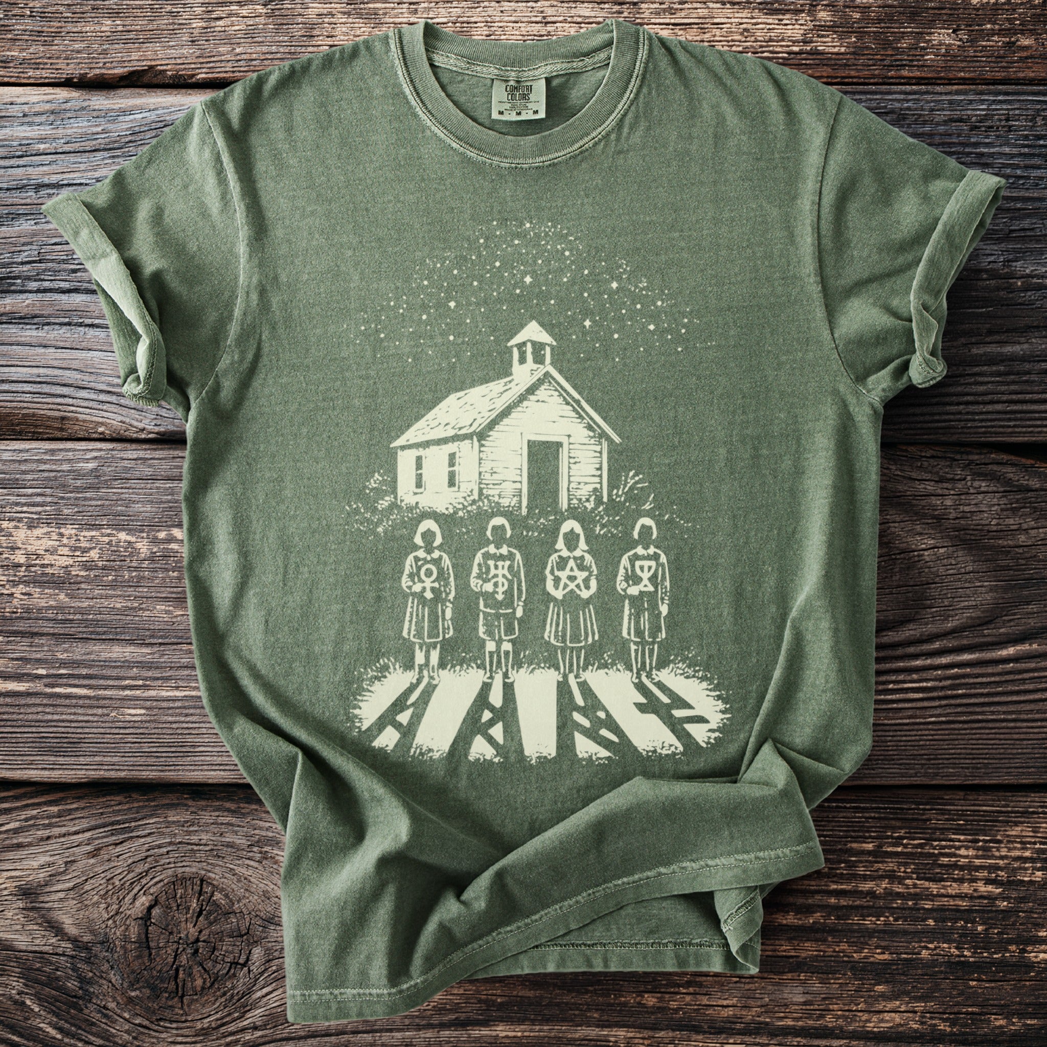 Green t-shirt with a white print of a schoolhouse, starry sky, and four figures with symbols.