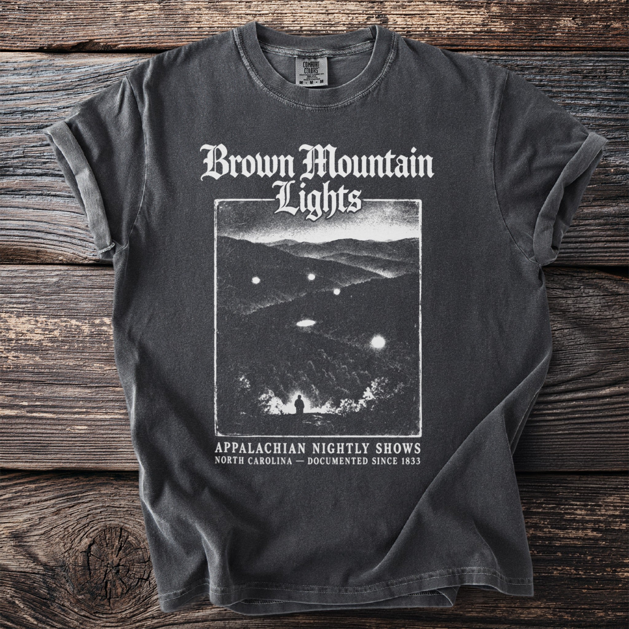 Brown Mountain Lights shirt with graphic of lights in mountains, "Appalachian Nightly Shows" text.