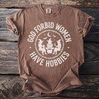 Brown t-shirt with graphic reading "God forbid women have hobbies" and witches.