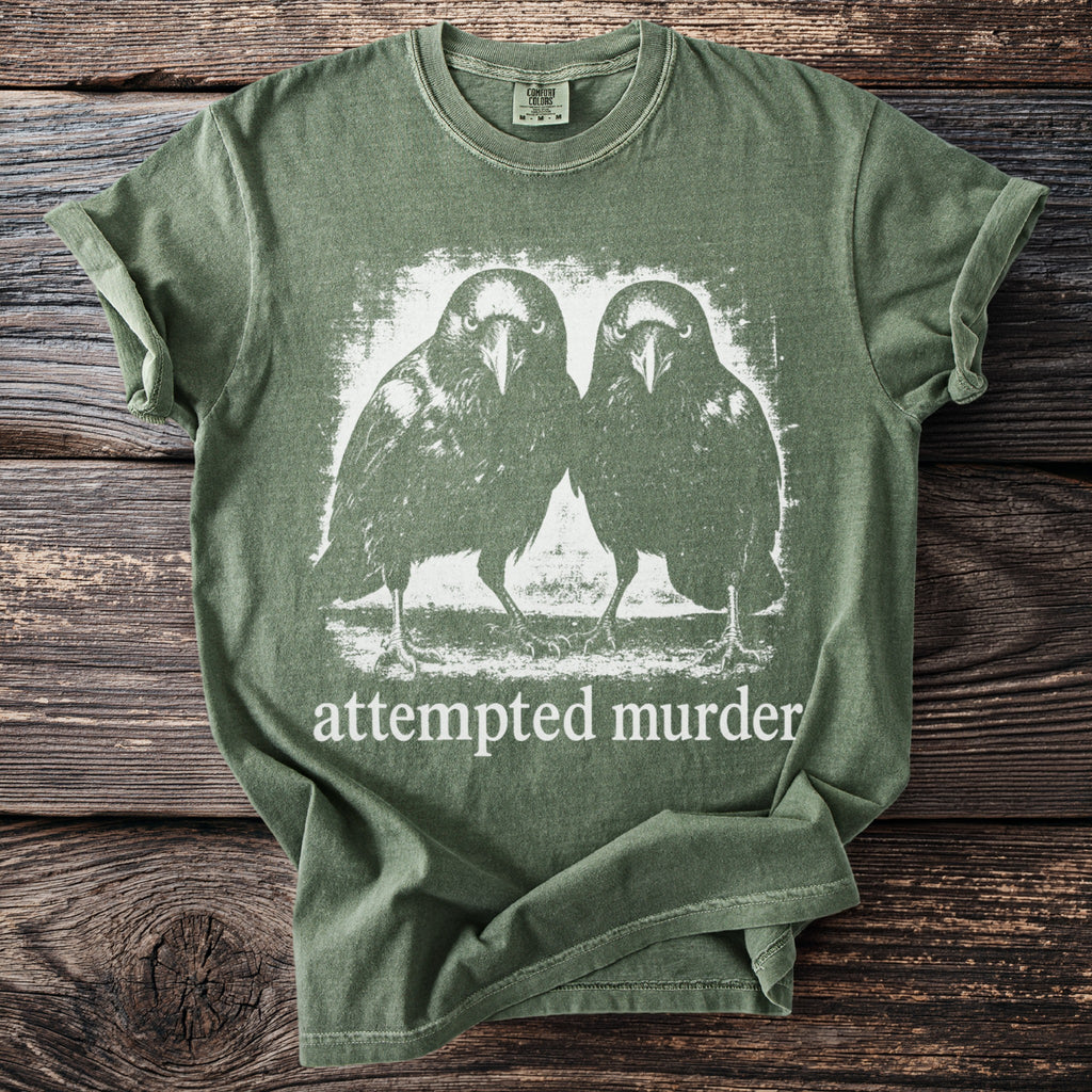 Green t-shirt with graphic of two crows and text "attempted murder".