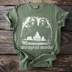 Green t-shirt with graphic of two crows and text "attempted murder".