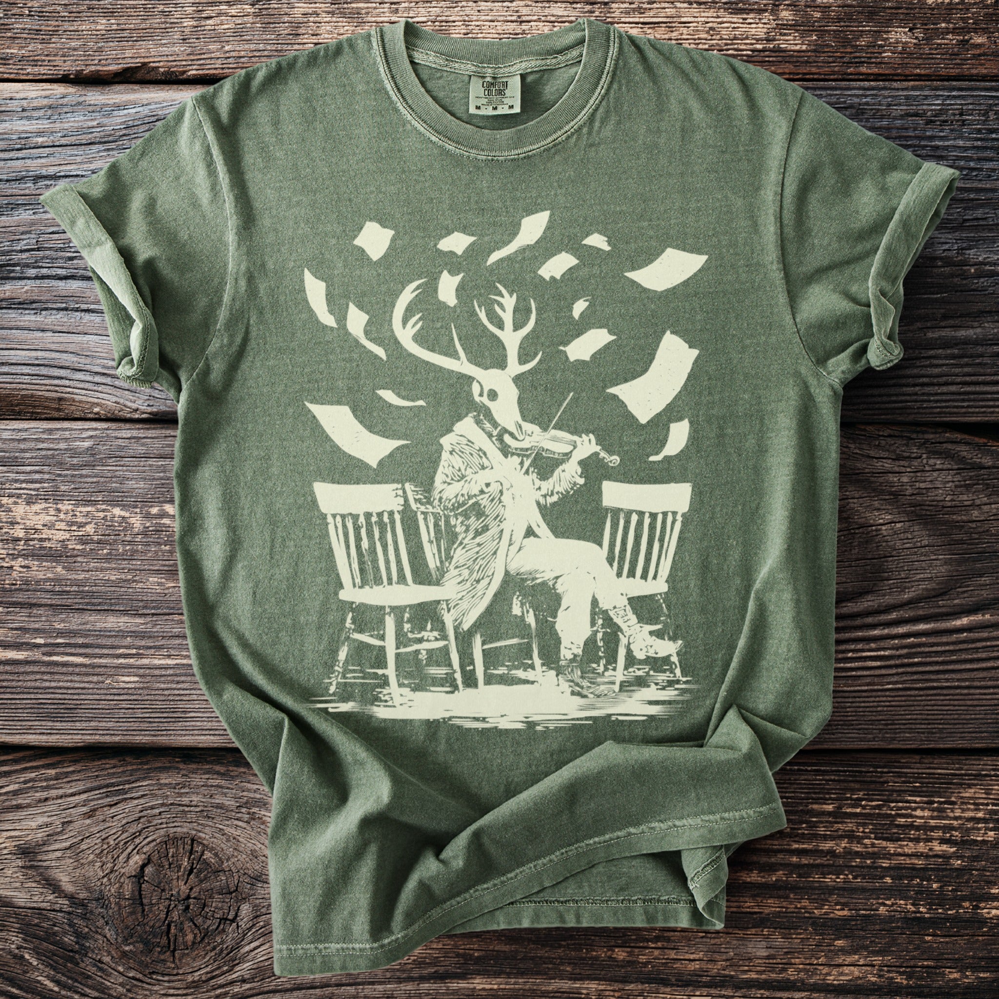 Green t-shirt with a beige graphic of a deer-headed figure playing a violin.