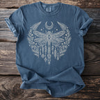 Blue t-shirt with white celestial dragonfly and floral design on a wooden background.