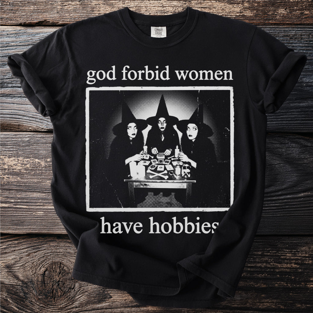 Black t-shirt with "god forbid women have hobbies" and three witches graphic.