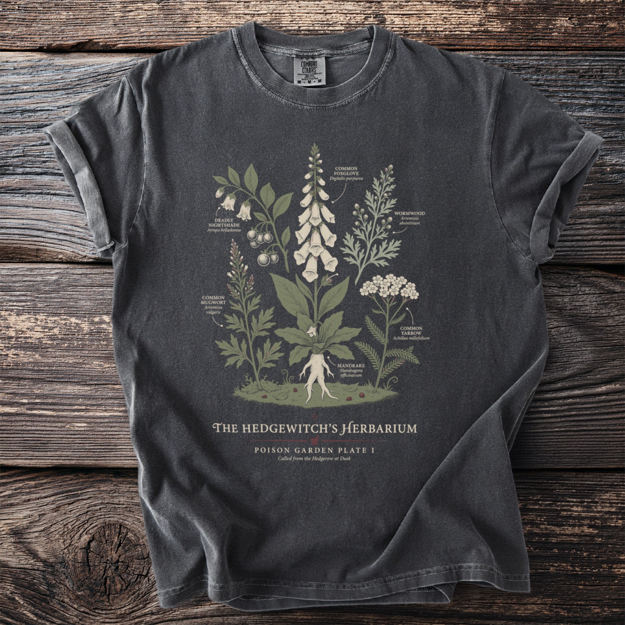 Dark t-shirt with an illustration of poisonous plants titled "The Hedgewitch's Herbarium".