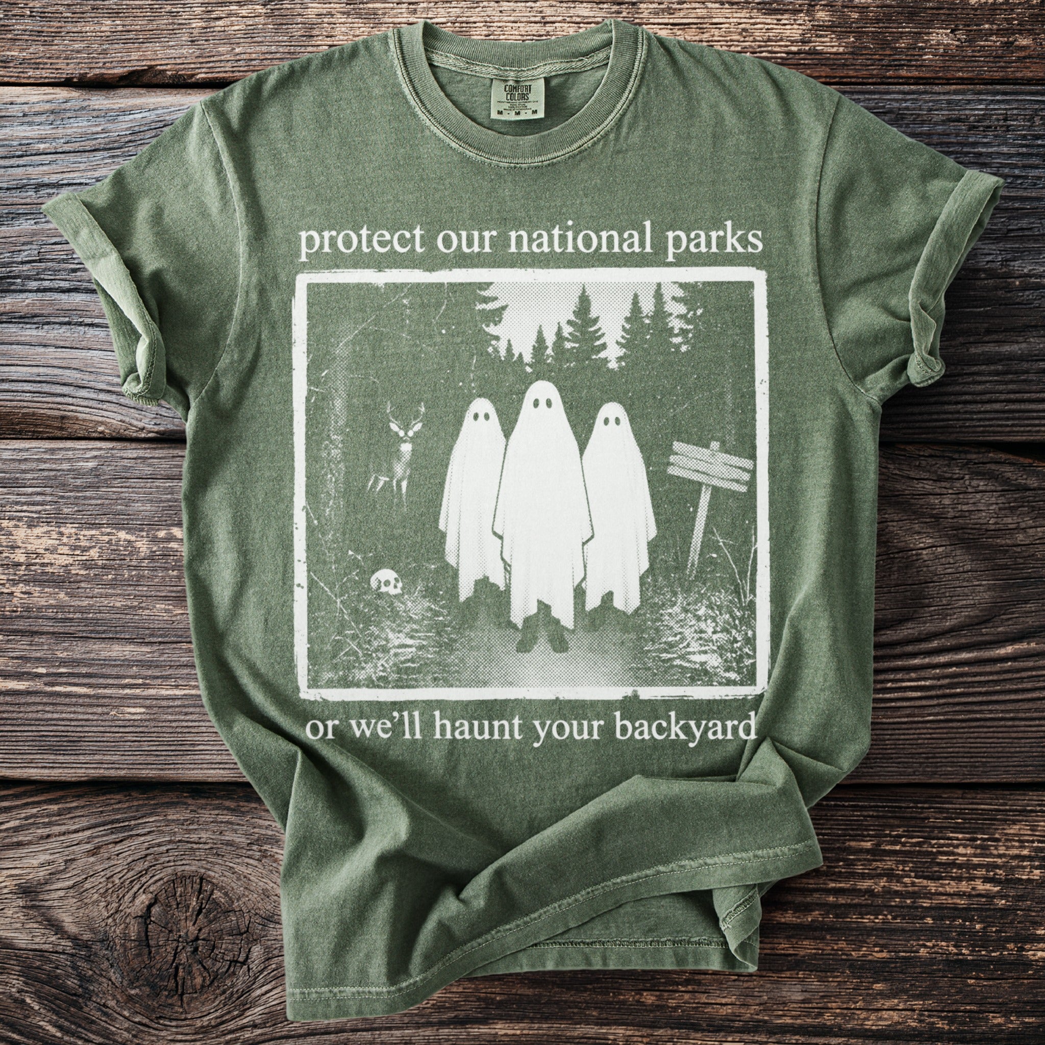Green t-shirt with text "protect our national parks or we'll haunt your backyard" and a ghost graphic.