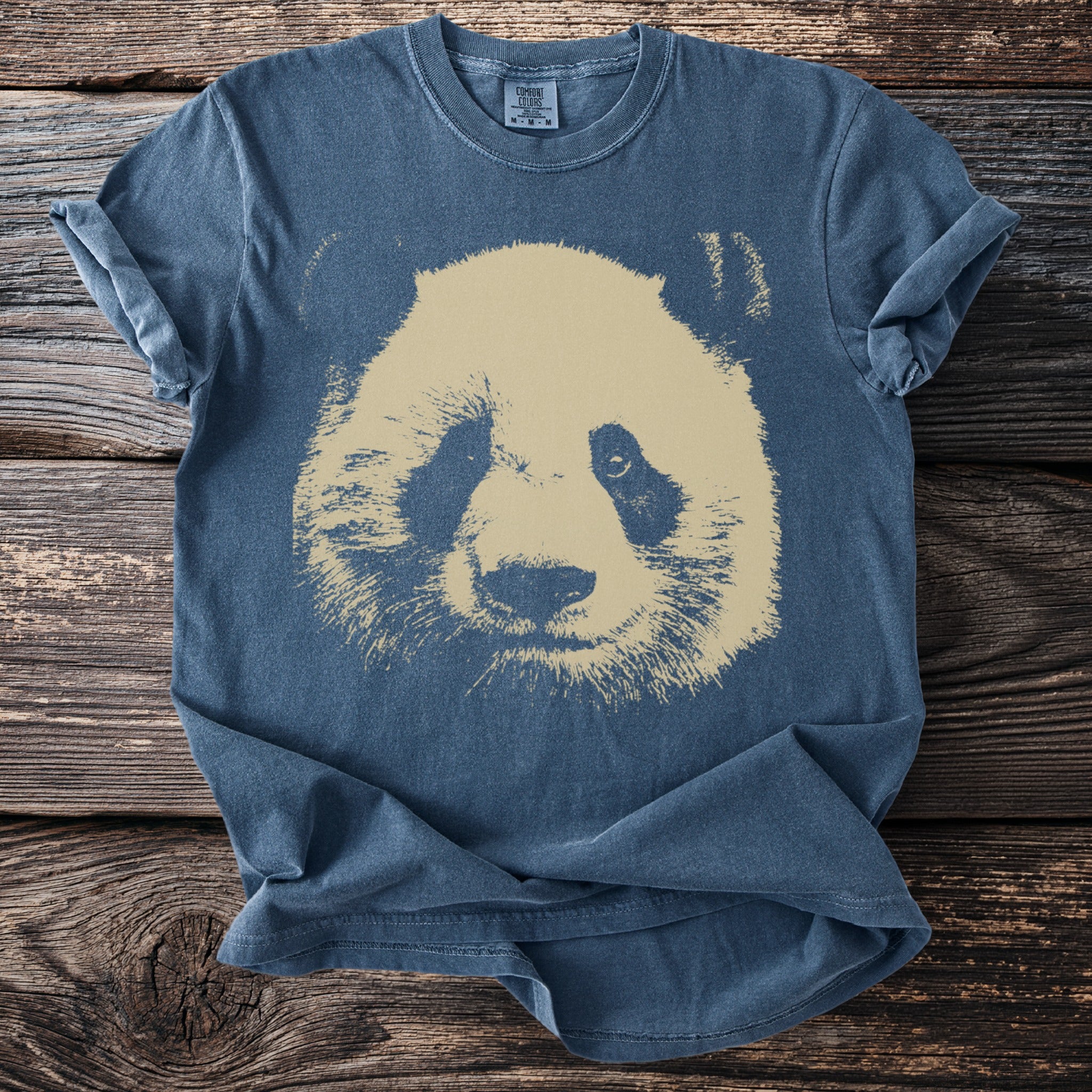 Blue Comfort Colors t-shirt with a faded tan panda face graphic across the chest.