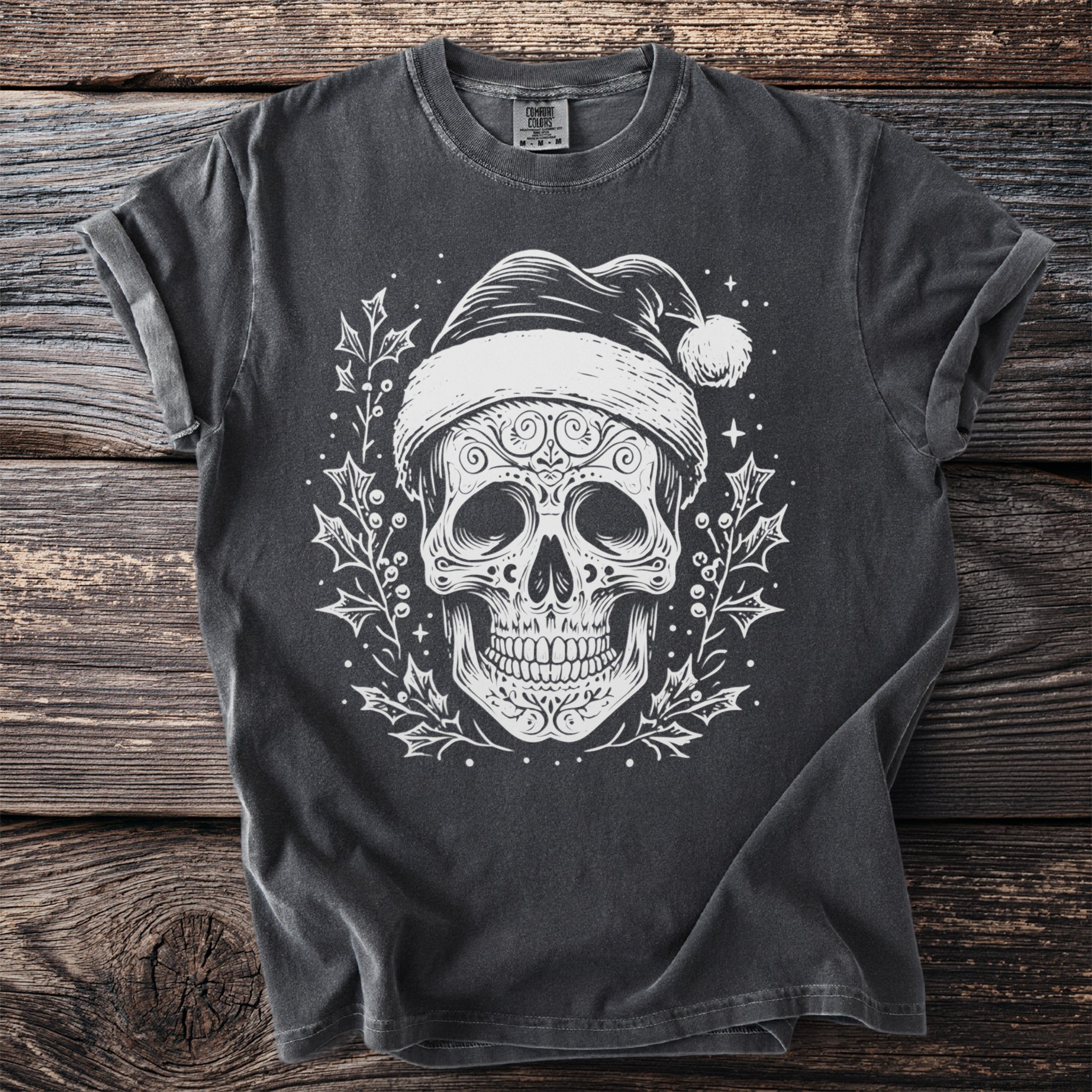 Dark t-shirt with white skull wearing Santa hat and holly graphic.