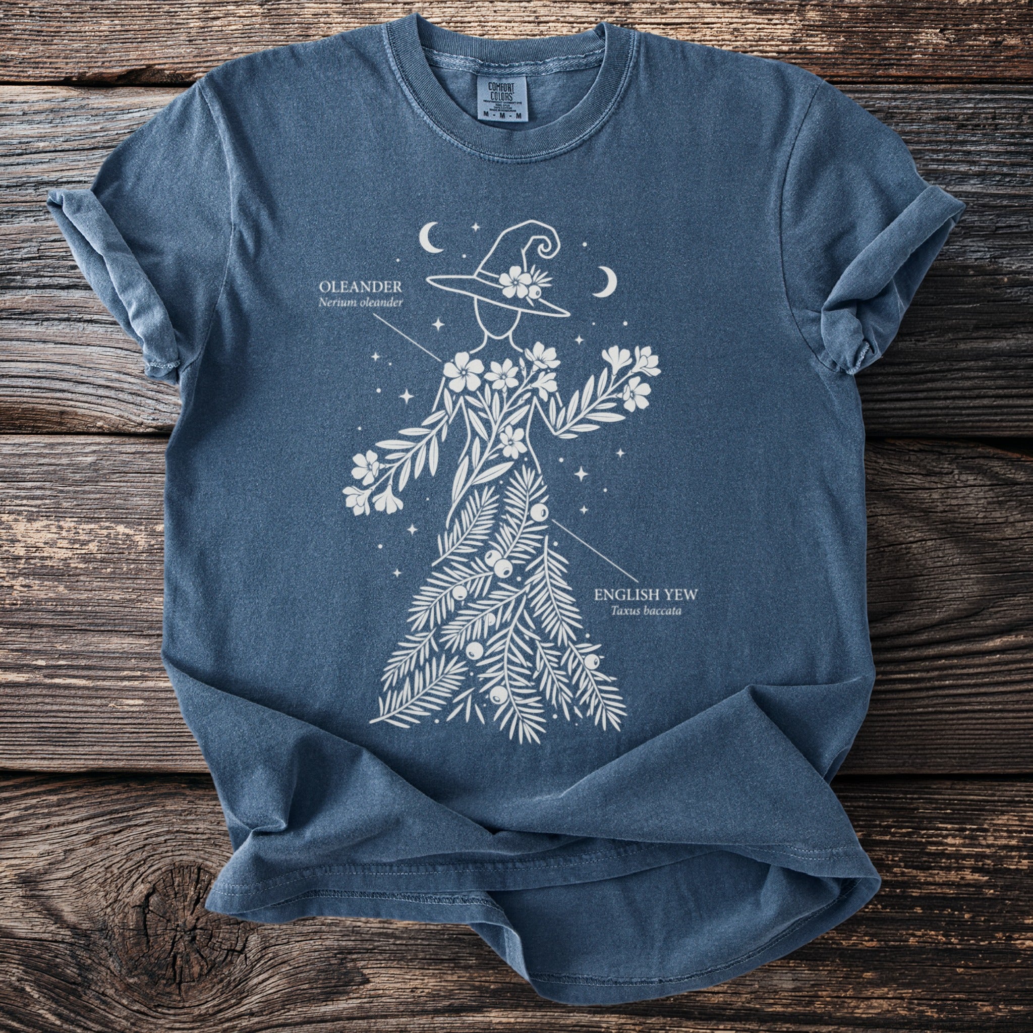 Blue t-shirt with white floral witch design, labeled Oleander and English Yew.