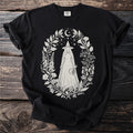 Black t-shirt with a cream floral oval design featuring a witch figure.