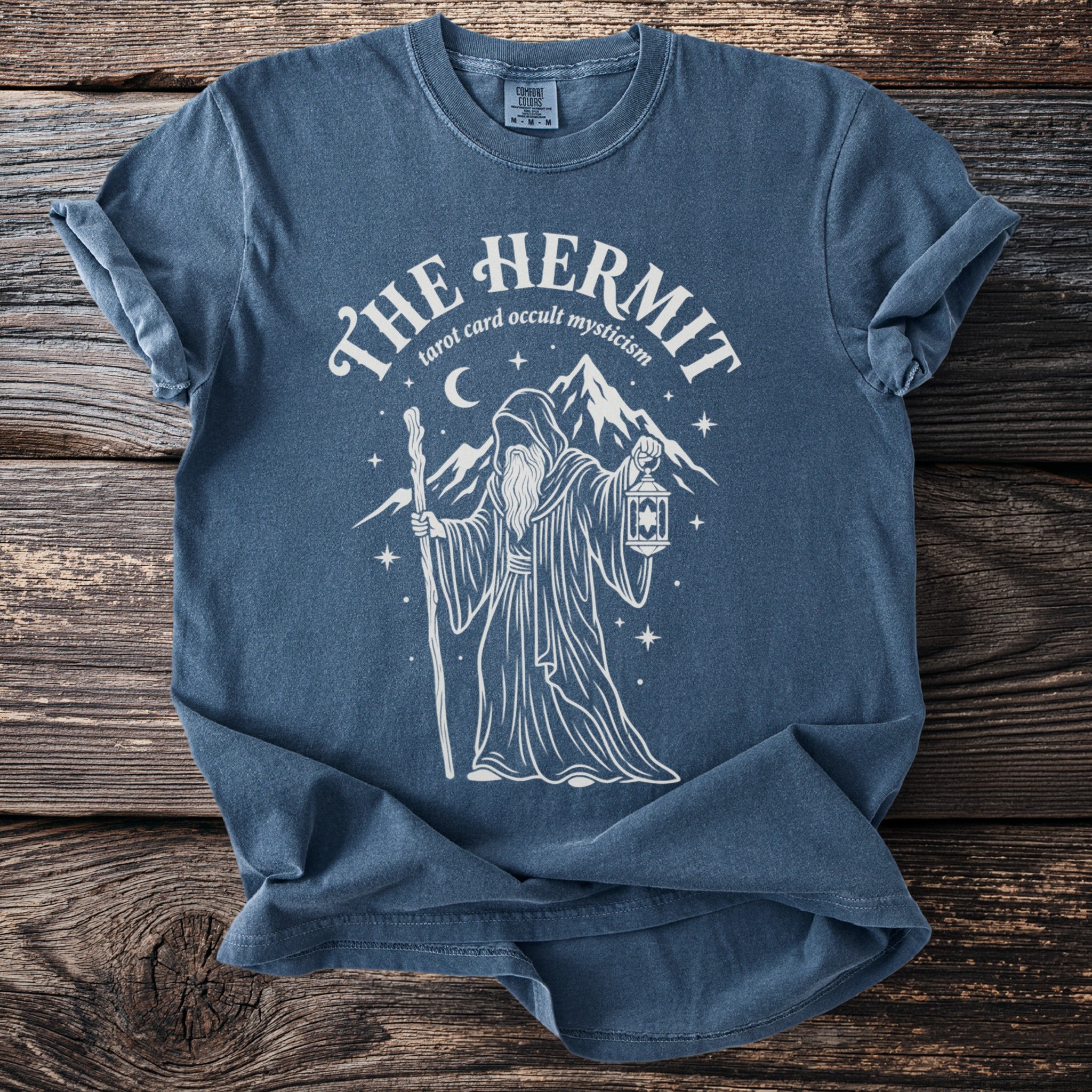 Blue t-shirt with The Hermit tarot card design, including a robed figure, lantern, and mountains.