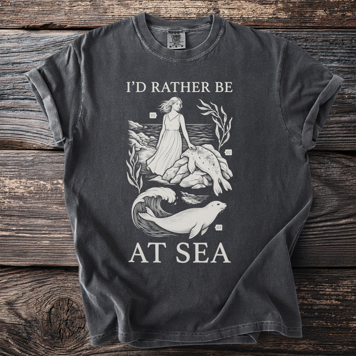 T-shirt with "I'd Rather Be At Sea" text and a graphic of a woman and seals.