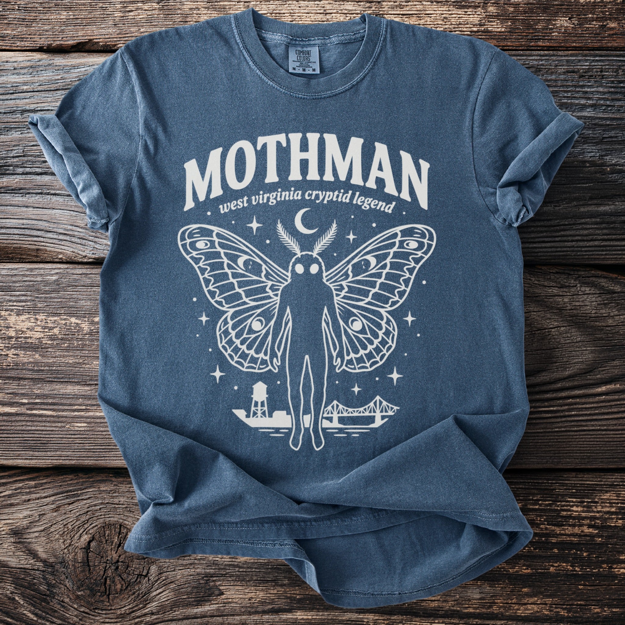 Mothman graphic t-shirt with moth wings, moon, stars, water tower, and bridge.