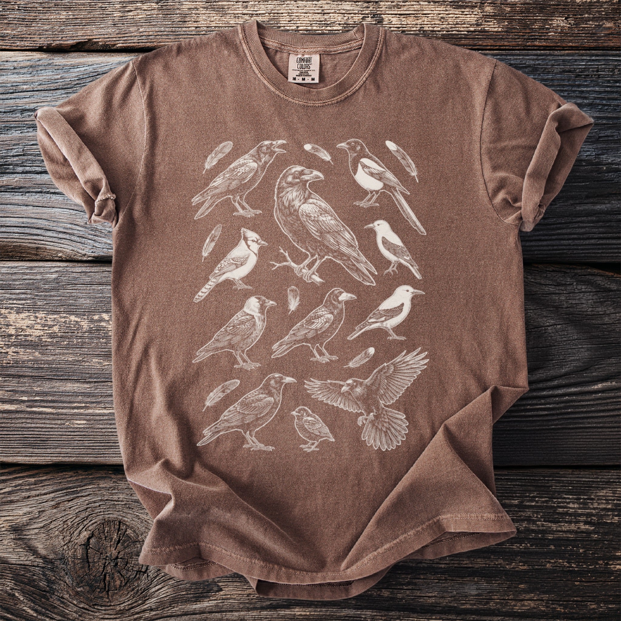 Brown t-shirt with a vintage-style sketch of various birds and feathers.