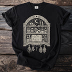 Black t-shirt with a cream-colored occult-themed shelf display with an open spellbook.