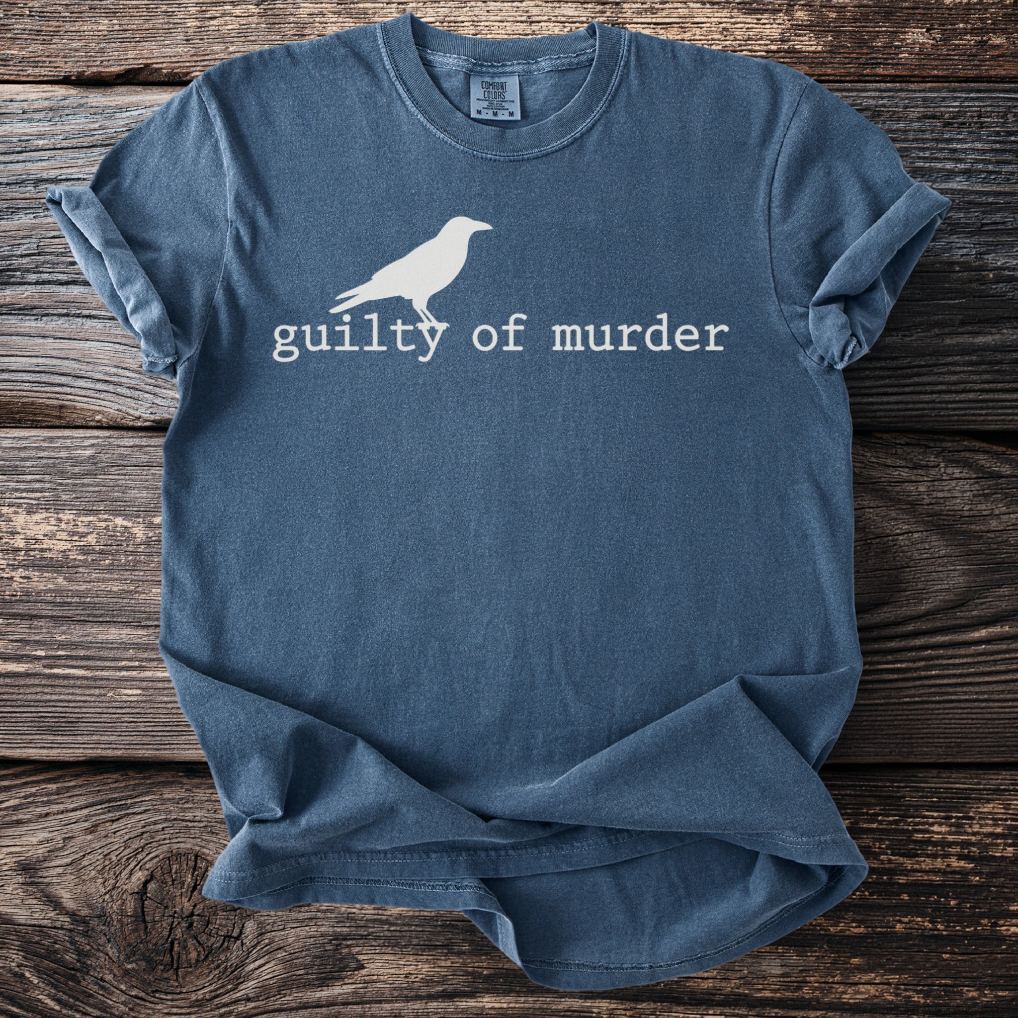 Blue t-shirt with white crow graphic and "guilty of murder" text.