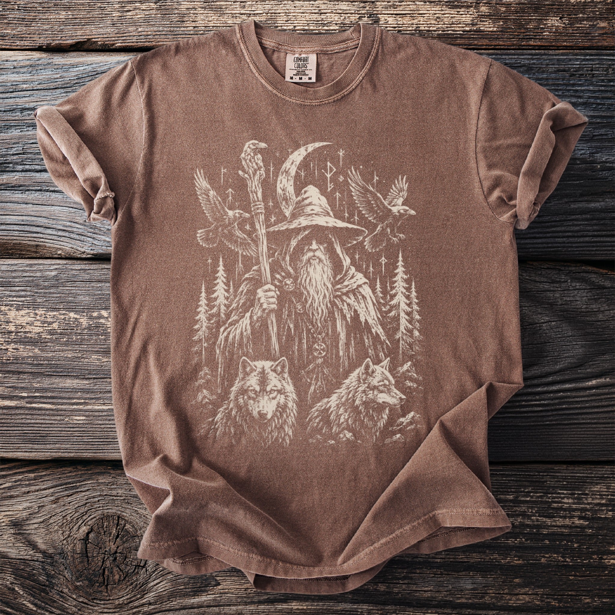 Brown t-shirt with a graphic of a wizard, wolves, ravens, and runes.