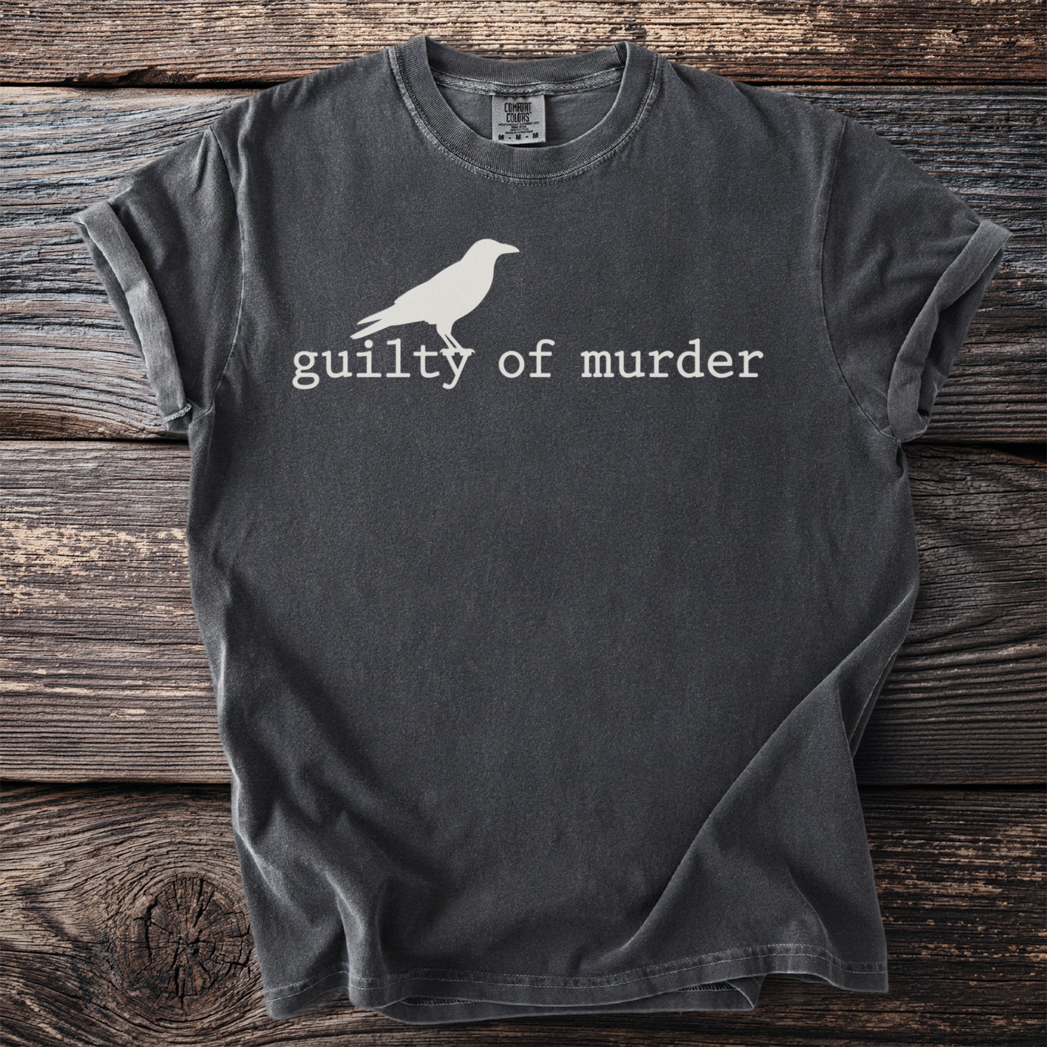 Dark grey t-shirt with a white crow graphic and text "guilty of murder".