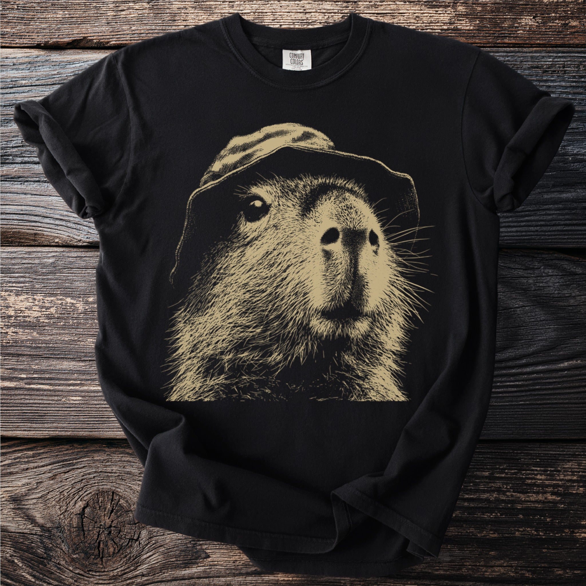 Black t-shirt with a beige illustration of a capybara wearing a hat.
