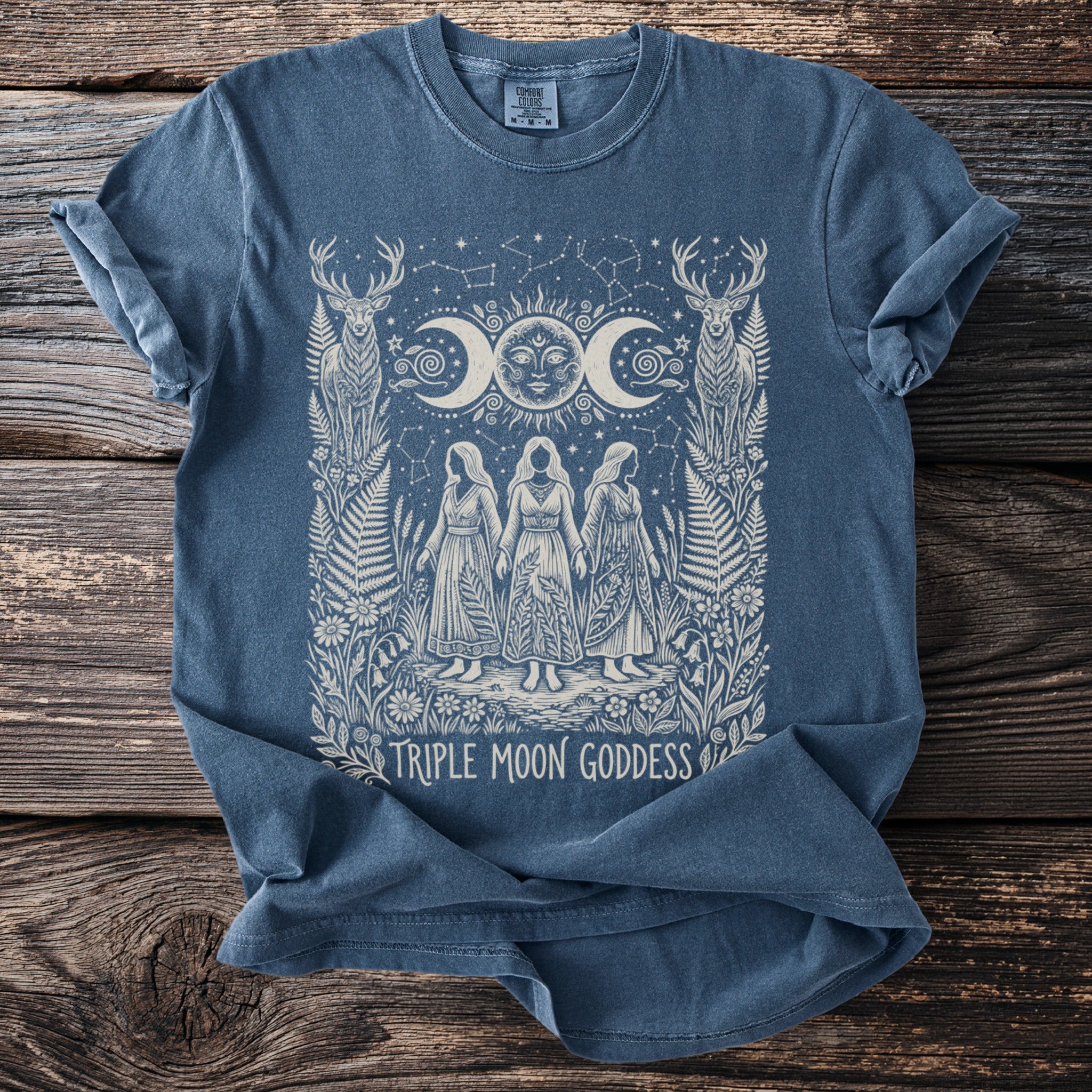 Blue t-shirt with a Triple Moon Goddess design featuring deer, moons, sun, and three women.