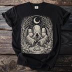 Black t-shirt with an illustration of cloaked figures around a campfire under a moon.