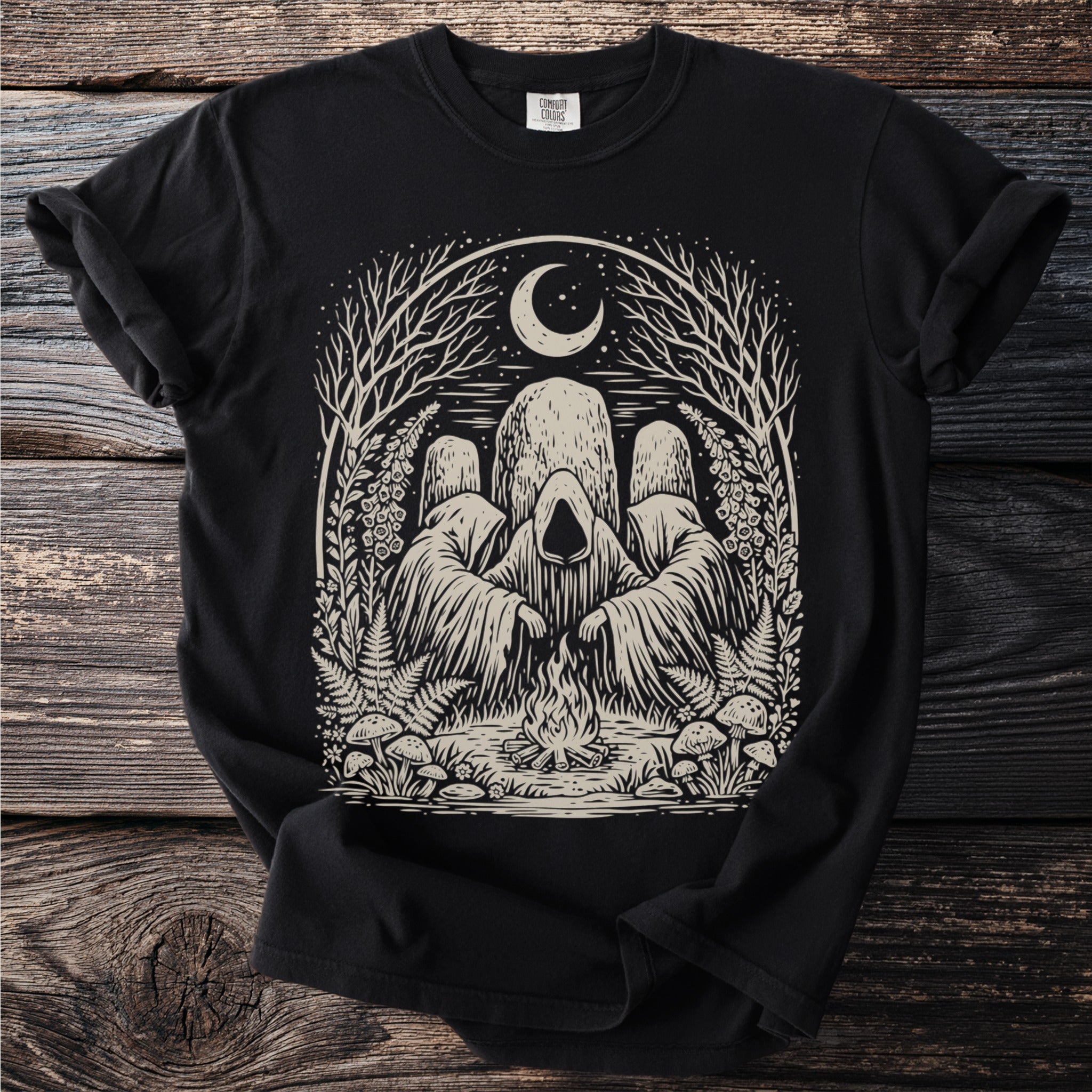 Black t-shirt with an illustration of cloaked figures around a campfire under a moon.