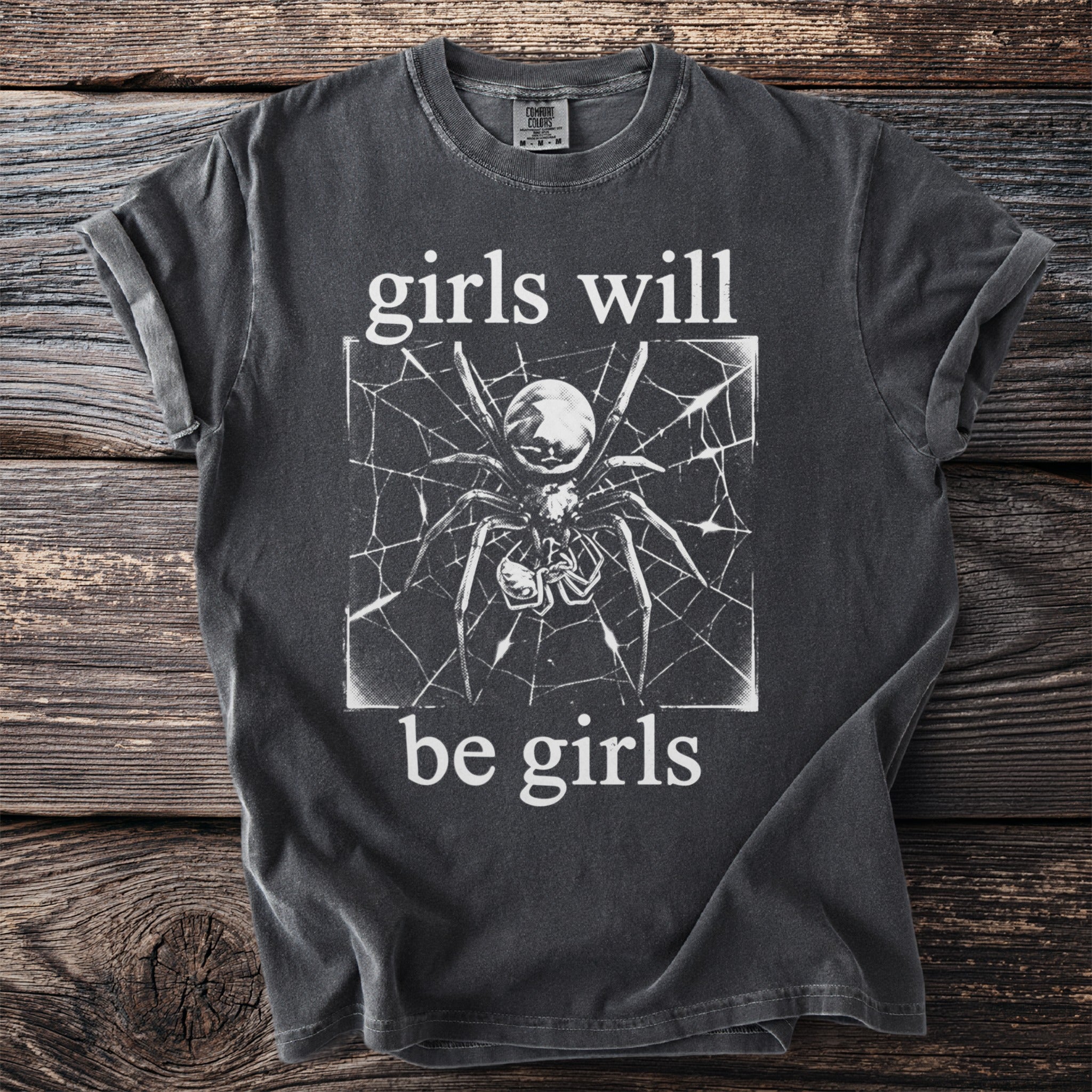 Dark grey t-shirt with white graphic "girls will be girls" and a spider on a web.