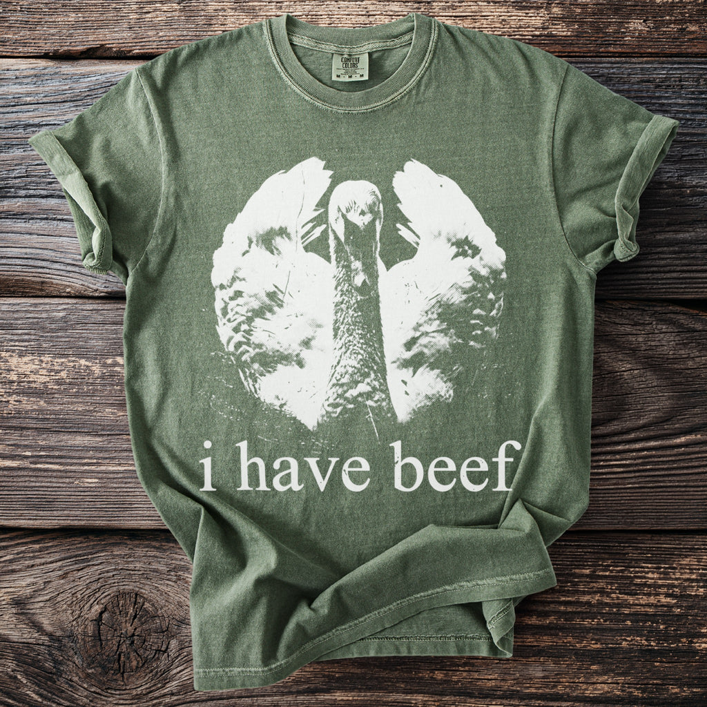 Green t-shirt with white graphic of a turkey and text that reads "i have beef."