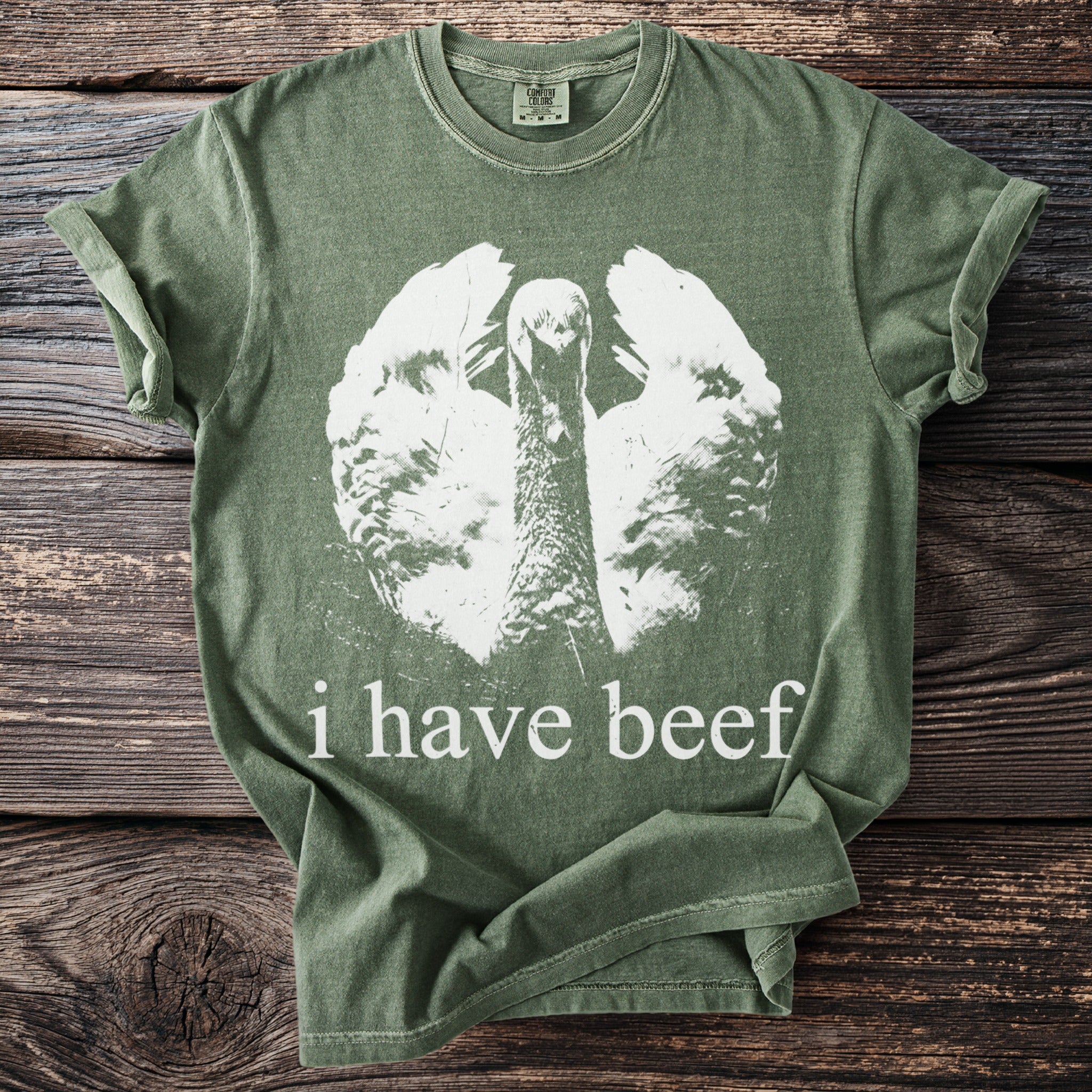 Green t-shirt with white graphic of a turkey and text that reads "i have beef."