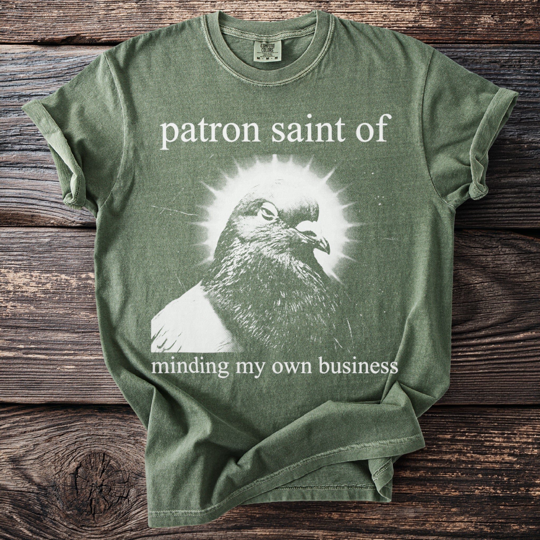 Green t-shirt with a pigeon graphic and text: patron saint of minding my own business.