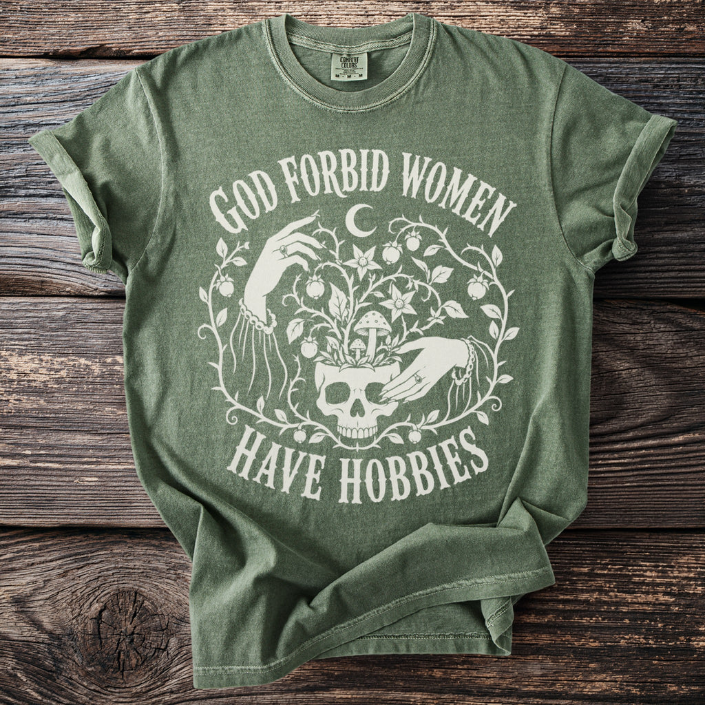 Green t-shirt with white text and graphics about women having hobbies.